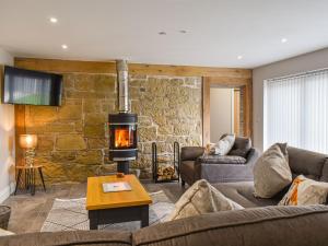 a living room with a stone wall and a fireplace at The Old Fox Lodge in Ruabon