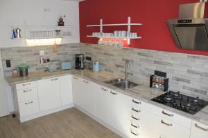 a kitchen with white cabinets and a sink and red wall at Ferienwohnung am Gilsbach in Borken
