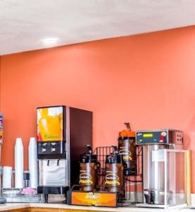 a kitchen with an orange wall with a coffee maker at Super 8 by Wyndham Mesa Gilbert in Mesa