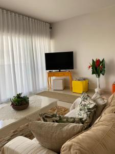 uma sala de estar com um sofá e uma televisão de ecrã plano em Bouganville Guest House BC em Balneário Camboriú