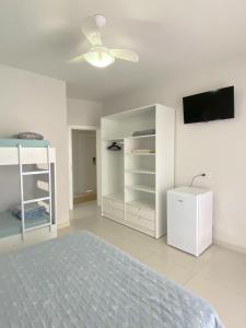 a white bedroom with a bed and a tv at Bouganville Guest House BC in Balneário Camboriú