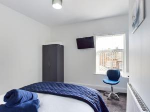 1 dormitorio con 1 cama y 1 silla azul en Whitmore House By RMR Accommodations - Newly Refurbed - Modern - Parking - Central en Etruria