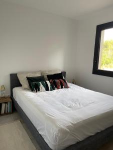 ein weißes Bett mit Kissen darauf im Schlafzimmer in der Unterkunft Rez de Jardin en pleine nature in Ventabren