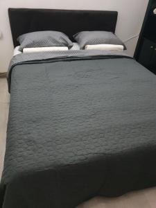 a black bed with two pillows on top of it at SB Apartman in Sremska Mitrovica
