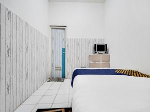 a bedroom with a bed and a tv on a wall at SPOT ON 91775 Pondok 14 Syariah in Bandung