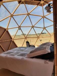 a bed in a yurt with a view of a field at A l'aube des sens in Bailly-le-Franc