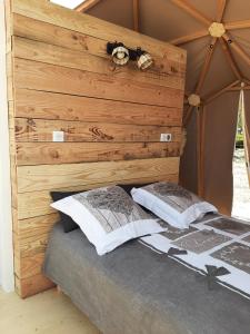 łóżko z drewnianym zagłówkiem i 2 poduszkami w obiekcie A l'aube des sens w mieście Bailly-le-Franc