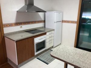 a kitchen with a stove and a refrigerator and a table at Casa Amelia in Mondariz-Balneario