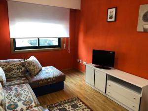een woonkamer met een bank en een flatscreen-tv bij Casa Amelia in Mondariz-Balneario