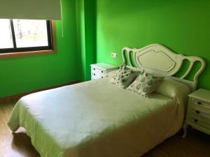 a green bedroom with a white bed and a window at Casa Amelia in Mondariz-Balneario