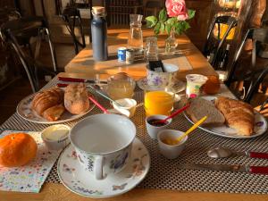 una mesa con platos de comida, tazas y cruasanes en Logis de La Roche - Niort - Chauray en Chauray