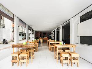 a row of wooden tables and chairs in a restaurant at SPOT ON 91781 Solo Baru Homestay Syariah in Jodoh