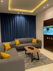 sala de estar con sofá y TV de pantalla plana en قمم بارك Qimam Park Hotel 2, en Abha