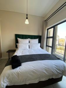 a bedroom with a large white bed and a window at Penthouse in Waterfall with backup power in Midrand