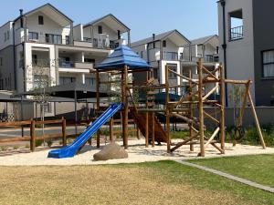 a playground with a blue slide and an umbrella at Penthouse in Waterfall with backup power in Midrand