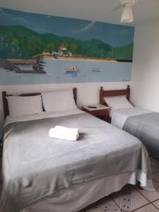 2 camas en una habitación con un cuadro en la pared en pedra do porto II, en Búzios