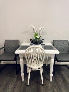 a white table with a vase of flowers on it at Centrally Located a Home from Home - Free Parking in Kent