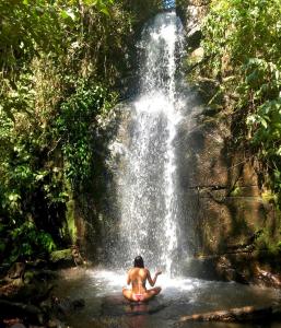 una mujer sentada frente a una cascada en Canto das Águas, en Alagoa