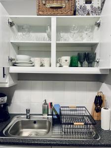 a kitchen sink with plates and dishes on shelves at Centrally Located a Home from Home - Free Parking in Kent