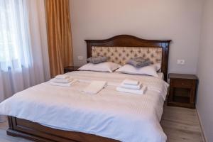 ein Schlafzimmer mit einem großen Bett mit zwei Handtüchern darauf in der Unterkunft Perla Dacilor in Grădiştea de Munte