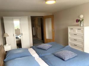 阿爾特納的住宿－SauerlandBlick，一间卧室配有两张带蓝色床单的床和梳妆台。