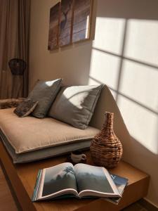 a couch with a book and a vase on a table at Ski Suites - A Luxury Maisonette Kalavryta in Kalavrita