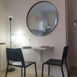 een tafel met twee stoelen en een spiegel aan een muur bij Studio à deux pas des étangs in Peyriac-de-Mer