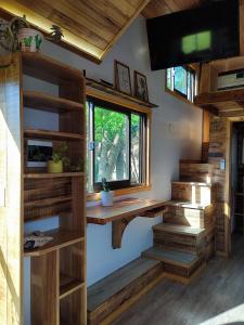 sala de estar con escaleras de madera y ventana en Tiny House Nativa en Montecarlo