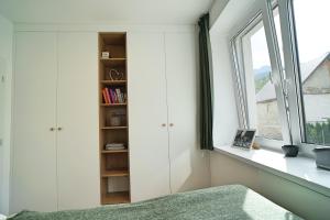 a bedroom with white cabinets and a window at Abbey Road Apartmán Iľanovo in Liptovský Mikuláš