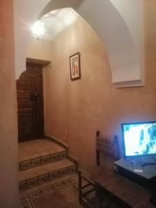a living room with a tv and a table and a door at Hostel Laksour in Marrakesh