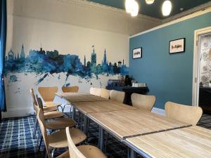 a room with tables and chairs and a painting on the wall at THE EDINBURGH TOWNHOUSE - Boutique Hostel in Edinburgh