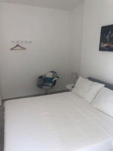 een slaapkamer met een wit bed en een stoel bij GUISCI BEACH HOUSE - 10 Passi dalla spiaggia in Sanremo