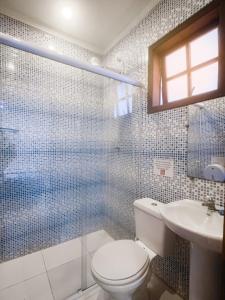 a bathroom with a toilet and a shower and a sink at Geko Pousada Paraty in Paraty