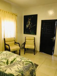 a bedroom with a bed and two chairs and a door at Serenity in Accra