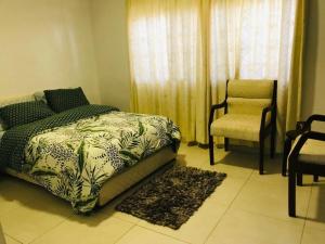um quarto com uma cama e uma cadeira em Serenity em Acra