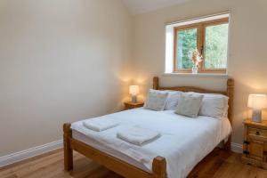 a bedroom with a bed with two lamps and a window at Beautiful barn conversion surrounded by woodland near Newark Show-ground 