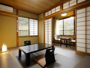 a room with a table and chairs and windows at Ryokan Kutsuroginoya Yuu in Takayama