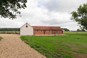 a large red and white barn in a field at Beautiful barn conversion surrounded by woodland near Newark Show-ground 