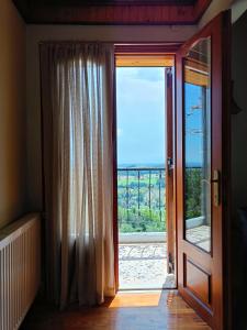 an open door to a balcony with a view of the ocean at Wooden Sofita House with Unlimited View in Grevena