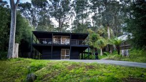 una casa negra con balcón en medio de una carretera en Peaceful country home in a middle of a rainforest, en Cockatoo