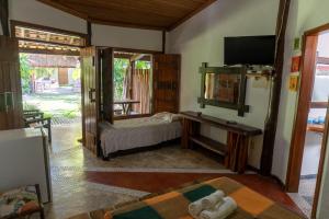 a living room with a bed and a television at Pousada Capitão Gancho in Barra Grande