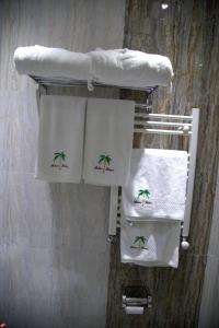 a towel rack with white towels with a palm tree on it at Palma Palace Hotel in Yerevan