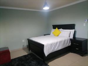 a bedroom with a bed with a yellow pillow on it at Queens And Kings Lodge in Durban
