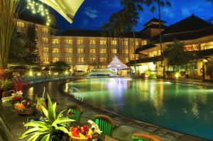 a hotel with a large swimming pool at night at Prime Plaza Hotel Purwakarta in Cikampek