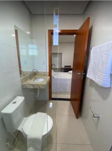 een badkamer met een toilet, een wastafel en een spiegel bij Hotel Vitória in Vitória da Conquista