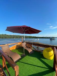 馬瑙斯的住宿－Casa Flutuante - Experiência única，一条船上的椅子和水边的雨伞