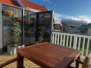 a deck with a wooden table on a balcony at Raglan Retreat on Gilmour in Raglan