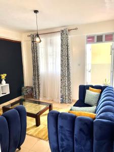 a living room with a blue couch and a glass table at Cozy 1br milimani in Kisumu