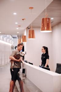 a man and woman standing at a reception counter with a dog at Level Seattle Downtown - South Lake Union in Seattle