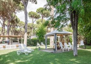 um gazebo com cadeiras brancas e mesas num quintal em La Meria di Maria La Terrazza em Marina di Grosseto